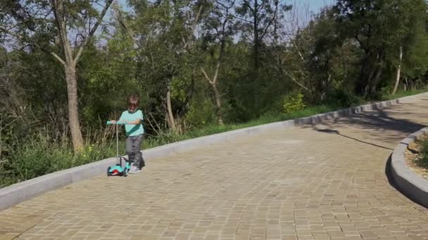 Mały chłopiec jeździ skuterem - Materiał filmowy, wideo