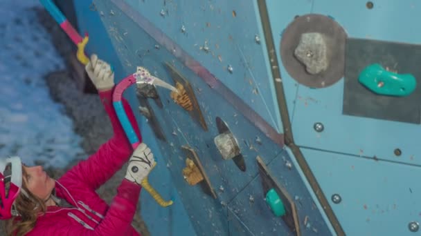 This young woman is carefully ice climbing with two cam hooks. She is also wearing a helmet. - Footage, Video