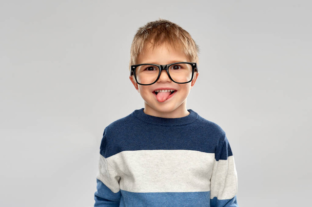 portrait of little boy in glasses showing tongue - Fotografie, Obrázek
