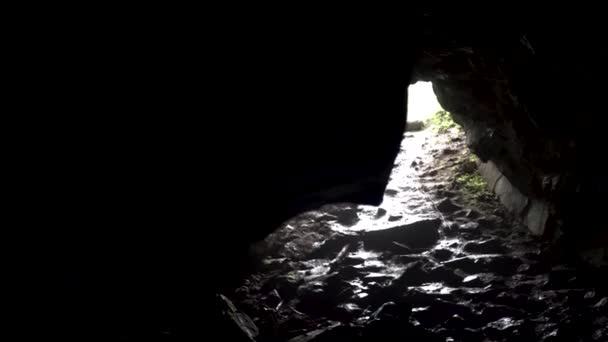 Helder zonlicht aan de uitgang van de donkere grot, mystieke natuur. Voorraadbeelden. Voorraadbeelden. Uitzicht vanaf de binnenkant van de ondergrondse tunnel of grot. - Video