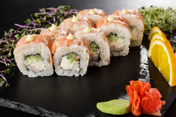 Sushi Rolls with cucumber, shrimp, crab meat and Cream Cheese inside on black slate isolated. Philadelphia roll sushi with shrimp. Sushi menu. Horizontal photo. - Photo, image
