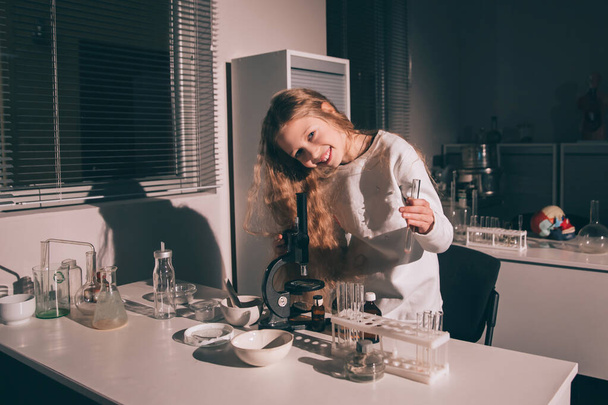 girl schoolgirl standing near the table in the chemistry room - Foto, afbeelding