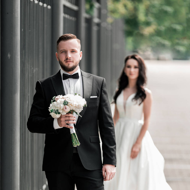 groom with a bouquet of flowers waiting for his bride on the city street - Fotoğraf, Görsel