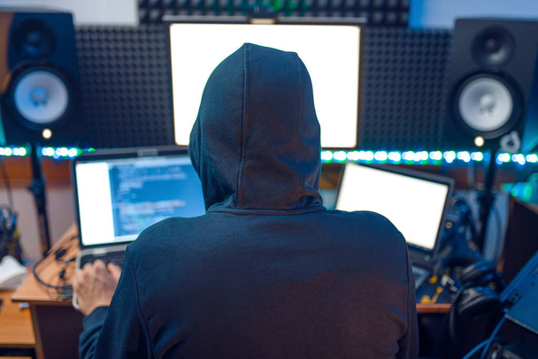 Hacker en el capó sentado en el ordenador portátil, vista trasera, piratería de información. espía de Internet, programador masculino tratando de hackear una red cifrada
 - Foto, imagen