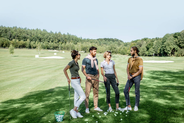 Amigos com equipamento de jogo em um campo de golfe
 - Foto, Imagem
