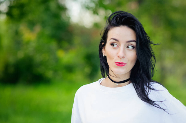Portrait of a cheerful girl in nature. with black hair and painted hoods in a white T-shirt. natural emotions. Beautiful smiling girl with open eyes. - Fotoğraf, Görsel