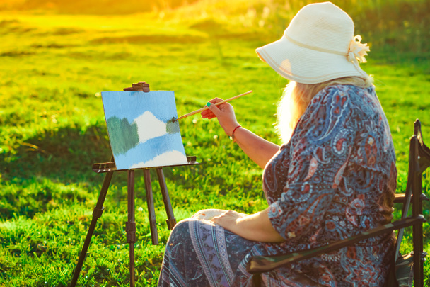 yaşlı bir kadın doğada bir resim boyar - Fotoğraf, Görsel
