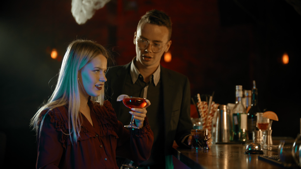 A man meeting a girl in the bar - standing by the stand and talking with young woman - drinking cocktails - Záběry, video