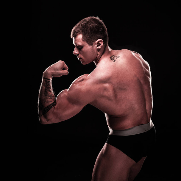 handsome bodybuilder guy showing biceps on his arm. - Φωτογραφία, εικόνα
