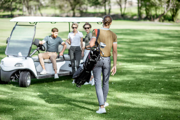 Οι άνθρωποι κοντά στο αυτοκίνητο του γκολφ στο γήπεδο του γκολφ - Φωτογραφία, εικόνα