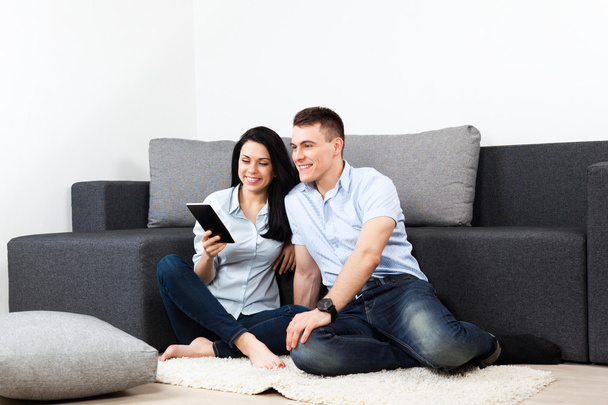 Young couple happy smilling using tablet touch screen pad at home - Photo, image