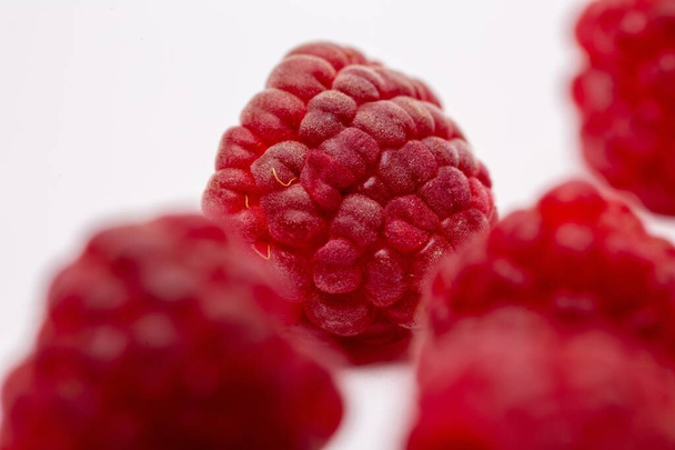 A closeup shot of fresh raspberries spread on a white background - perfect for a food blog - 写真・画像