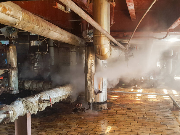 パイプから蒸気だ生産における圧力の下で工場の故障だガス漏れだ配管の多くとヒートパイプライン内部産業用ガス中の蒸気の漏れ。工場での蒸気バルブ配管  - 写真・画像