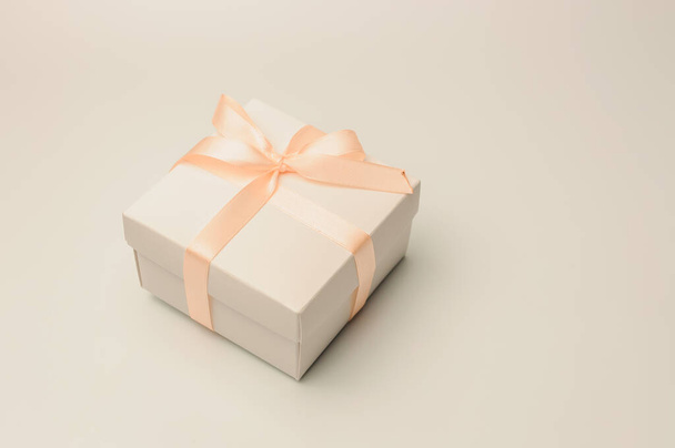 Подарочная коробка с бежевой лентой на белом фоне, изолировать. Авторское пространство. Концепция продаж, скидок, рождественских подарков и покупок
. - Фото, изображение