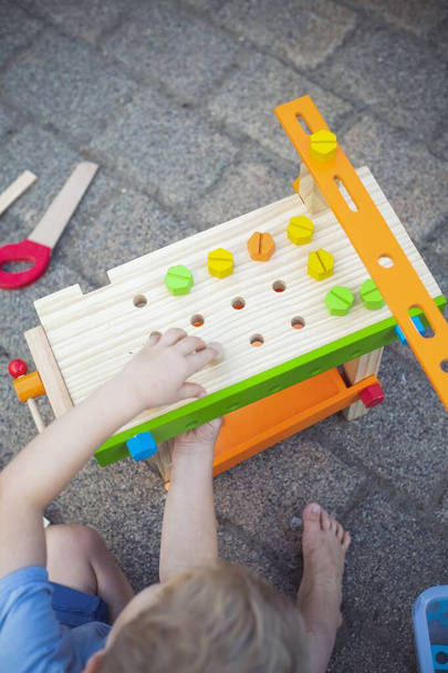 A vertical high angle shot of a kid playing with toys in the backyard during daytime - 写真・画像