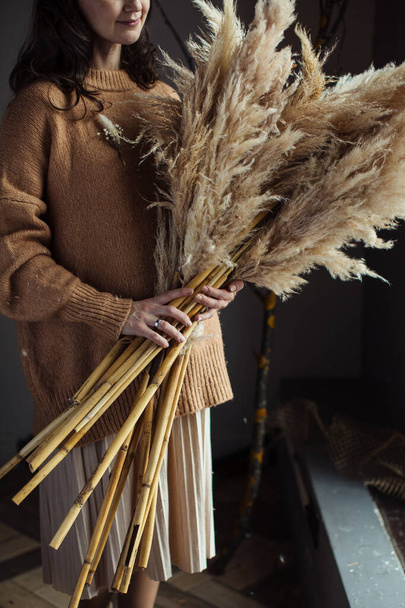 Hermoso ramo de otoño de materiales secos en las manos de una mujer. Cortaderia
 - Foto, Imagen