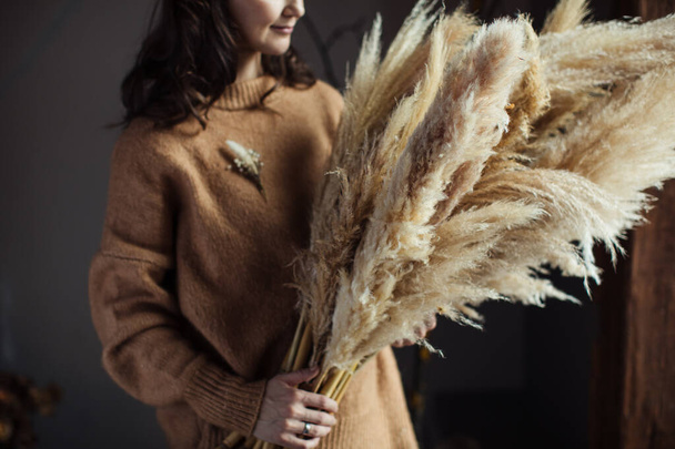 Beautiful autumn bouquet of dry materials in the hands of a woman. Cortaderia - Foto, Imagen