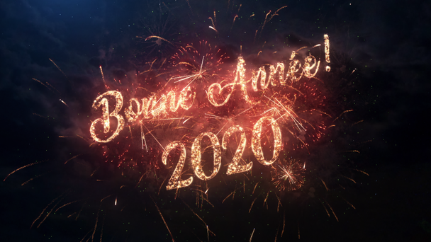 2020 Happy New Year begroetingstekst in het Frans met deeltjes en vonken op zwarte nachtelijke hemel met gekleurd slow motion vuurwerk op achtergrond, mooie typografie magisch ontwerp. - Video