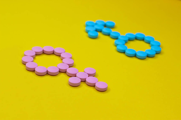 Female hormones estrogen: estradiol, estriol and progesterone and male hormone testosterone. Gender signs from pills on yellow background. Anabolic. - Photo, image
