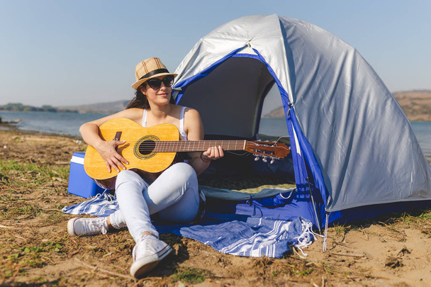 Woman tourist with guitar sitting next to tent. - Foto, Imagem