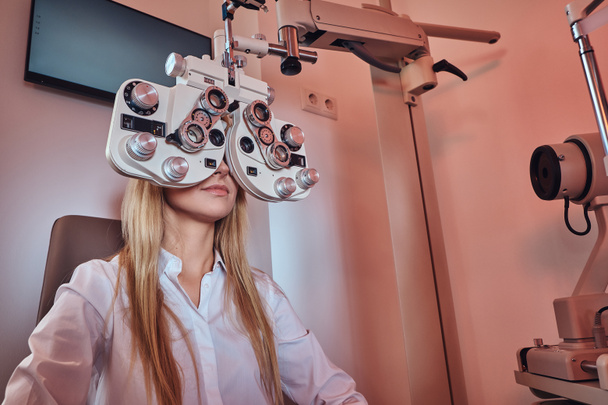 A nő ellenőrzi a látását az optikás szekrényben. - Fotó, kép