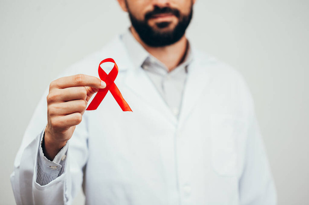 Punainen nauha HIV-sairaustietoisuuteen lääkärin kädessä, 1. joulukuuta Maailman aids-päivän käsite
. - Valokuva, kuva