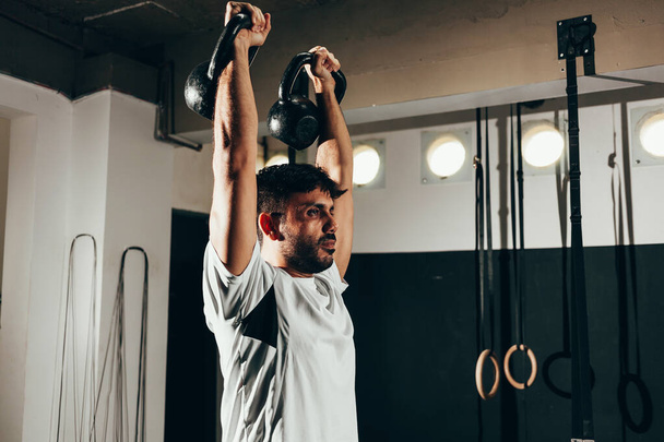 Man aan het trainen met een kettlebell in een sportschool - Foto, afbeelding