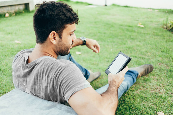 Young man reading e-book in the park - Foto, imagen