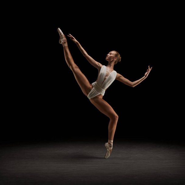 Ballerina in white costume and pointe shoes dancing on the stage - Fotó, kép