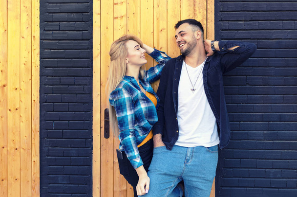 Loving diverse young couple in love isolated on wall looking at each other dreaming about their future together - Happy smiling latin man and caucasian woman embracing and having fun playing outdoor - Foto, imagen