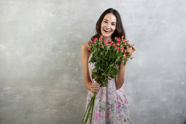 Κοντινό πλάνο πορτρέτο της ελκυστική νεαρή γυναίκα σε καλοκαιρινό φόρεμα κρατώντας μπουκέτο τριαντάφυλλα, κορίτσι ευτυχισμένη - Φωτογραφία, εικόνα