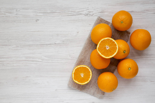 Čerstvé zralé organické pomeranče na bílém dřevěném povrchu, pohled shora.  - Fotografie, Obrázek