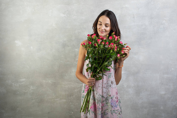 Close-up portrait of attractive young woman in summer dress holding bouquet of roses, girl happy - Fotó, kép