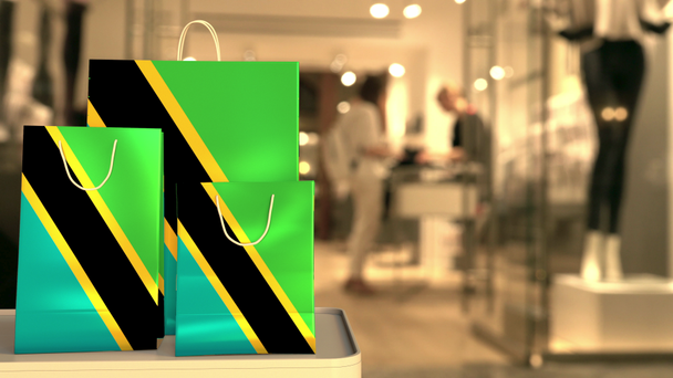 Flag of Tanzania on the paper shopping bags against blurred store entrance. Retail related clip - Πλάνα, βίντεο