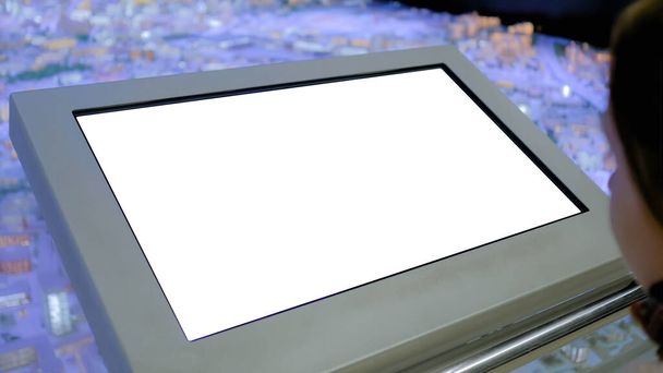Женщина смотрит на пустой белый киоск дисплея на выставке - концепция белого экрана - Фото, изображение