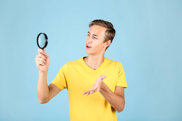 Young man with magnifying glass on blue background - Photo, image