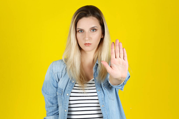 Young woman showing hand palm on yellow background - Φωτογραφία, εικόνα