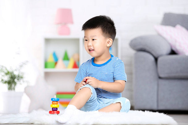 Beautiful boy sitting and playing with rainbow toy at home - Foto, Imagen