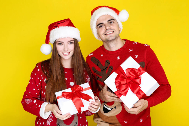 Mooie man en vrouw in kerst truien en santa hoeden hol - Foto, afbeelding