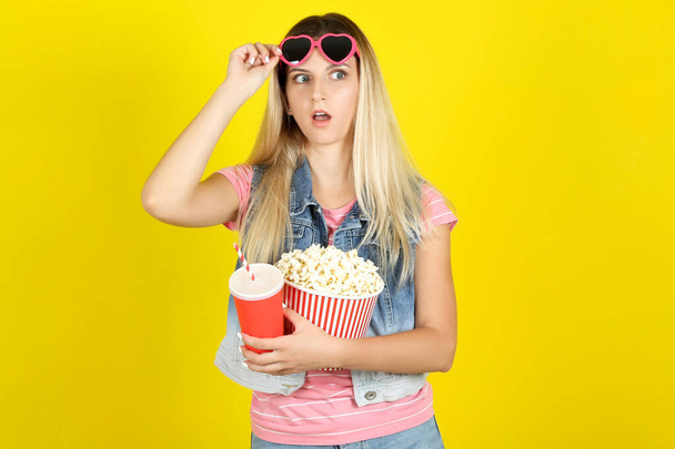 Young woman in sunglasses holding bucket with popcorn and paper  - Photo, Image