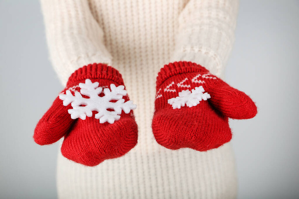 Hands in knitted mittens holding snowflakes on grey background - Foto, Bild