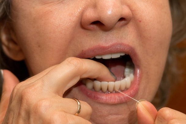 Femme soie dentaire ses dents pour une bonne hygiène dentaire
 - Photo, image