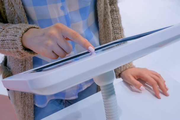 Mujer mano utilizando pantalla táctil de pie quiosco tableta blanca - Foto, Imagen