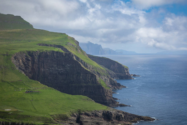 View on the Mykines island with moody clouds covering the top of - Photo, Image