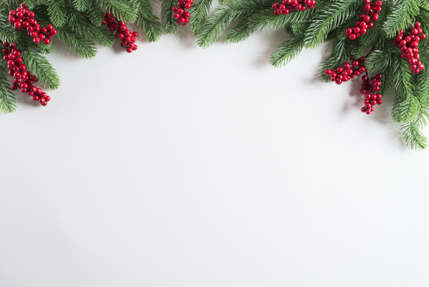 Vánoční pozadí konceptu. Pohled shora vánoční dárek box červené koulí s smrkové větve, šišky, červené bobule a zvonek na bílém pozadí. - Fotografie, Obrázek