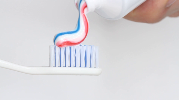 Nakładanie pastę do zębów na szczoteczkę na białym tle - Materiał filmowy, wideo