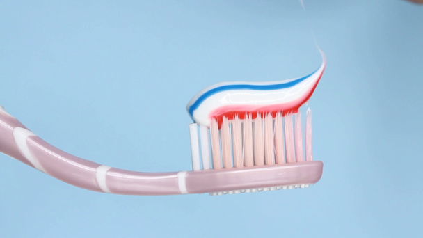 Mettre du dentifrice sur un pinceau sur fond bleu
 - Séquence, vidéo