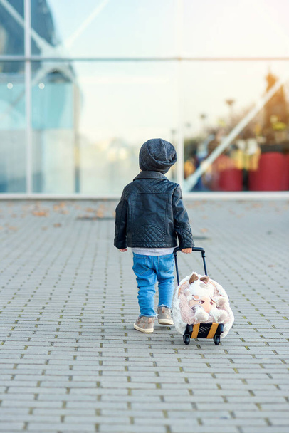 Cute little traveler girl pulls pink suitcase towards the airport. - Fotoğraf, Görsel