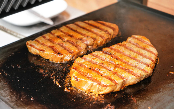 Dva vepřové steaky grilované na elektrickém grilu, kovová deska - Fotografie, Obrázek