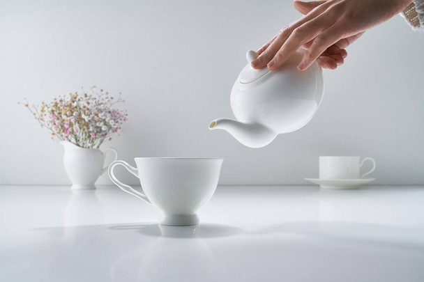 Composition avec thé en porcelaine blanche sur fond gris clair avec un délicat bouquet de fleurs
 - Photo, image
